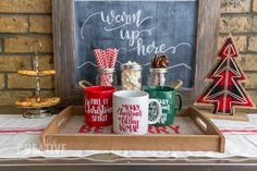 coffee mugs are sitting on a tray in front of a chalkboard with the words merry up here