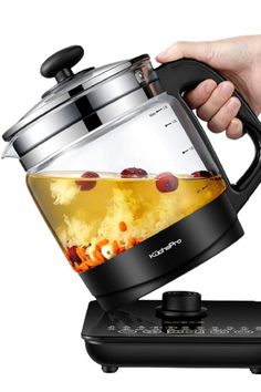 a person is pouring tea into a kettle on top of an appliance with the lid open