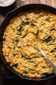 a skillet filled with macaroni and cheese on top of a wooden table