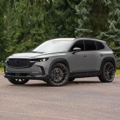 a grey suv parked in front of some trees