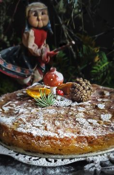 a cake sitting on top of a table covered in powdered sugar and pine cones