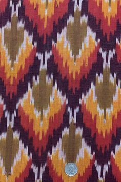 an orange, red and yellow pattern on fabric with a button in the middle that says