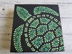 a black and green painting on wood with dots in the shape of a sea turtle