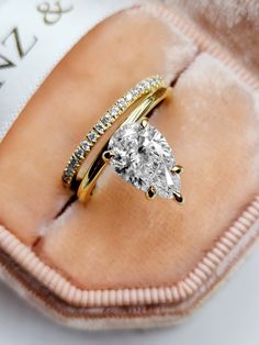 an engagement ring with a pear shaped diamond on it in a pink velvet box,