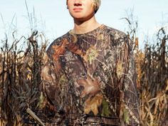 a young man standing in front of a cornfield with his hands on his hips