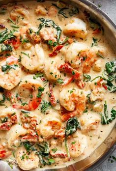 a pan filled with shrimp and spinach covered in sauce on top of a table