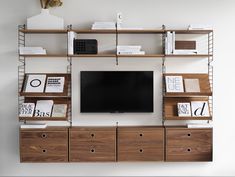 an entertainment center with shelves, drawers and a flat screen tv mounted on the wall