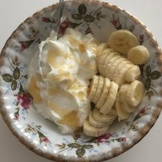 a bowl filled with yogurt and bananas on top of a floral print plate