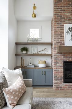 a living room filled with furniture and a fire place in front of a brick wall