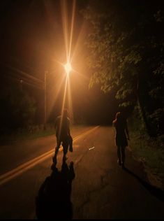 two people walking down the road at night