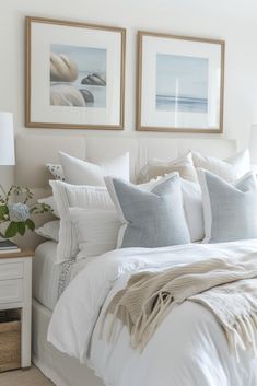 a bed with white linens and pillows in a bedroom next to two pictures on the wall