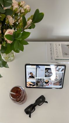 an image of a tablet with glasses and flowers on the table in front of it