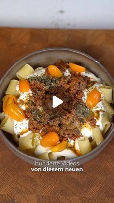 a bowl filled with pasta and sauce on top of a wooden table