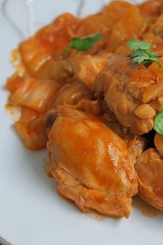 a white plate topped with meat covered in sauce and garnished with parsley