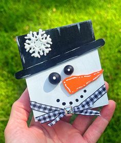 a hand holding a small snowman made out of paper