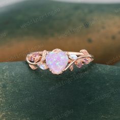 an opal and diamond ring on top of a rock