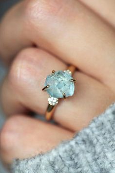 a woman's hand holding a ring with an aqua blue topazte and diamond accents