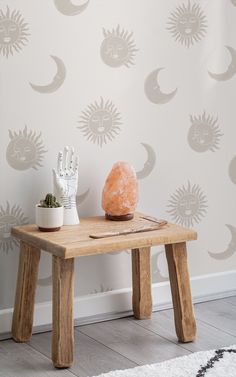 a wooden table topped with an orange rock next to a wallpaper covered in sun and moon designs