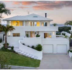 a large white house with palm trees in the front yard and stairs leading up to it