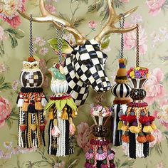 three deer head ornaments hanging from hooks on a floral wallpapered wall with pink flowers