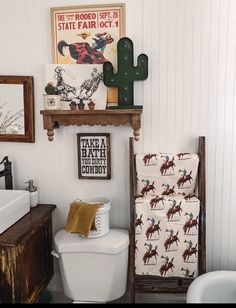 a white toilet sitting in a bathroom next to a wooden shelf with pictures on it