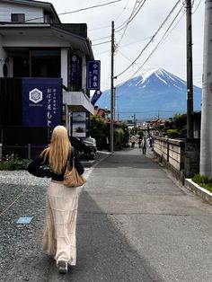 a woman walking down the street in front of a mountain