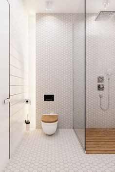 a white bathroom with a wooden toilet seat and shower head mounted to the side of the wall