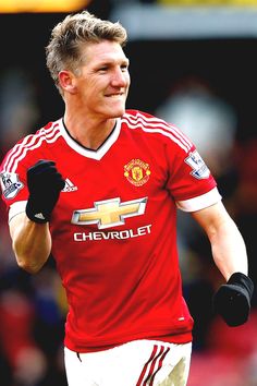 man in red jersey running on soccer field with black gloves and white shorts, smiling