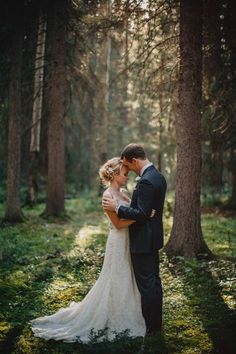 a bride and groom are standing in the woods hugging each other with their arms around each other