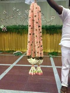 a man holding up a bunch of flowers on top of a pole in front of a stage