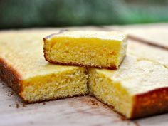 three pieces of yellow cake sitting on top of a wooden table next to each other