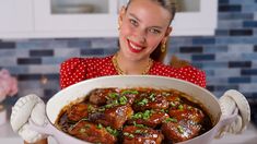 a woman is holding a large bowl of food