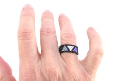 This beaded ring features three triangles in the colors of the asexual flag: gray, white and purple. The triangles are woven on a black seed bead band. ElephantBeads rings work beautifully as: - Thumb rings - Pinky rings - Toe rings See other Pride jewelry here: https://www.etsy.com/shop/ElephantBeads?ref=hdr_shop_menu%C2%A7ion_id&search_query=pride+jewelry Sizing your ring is very important, as ElephantBeads rings are woven tight and strong (not stretchy). See FAQs below for an easy guide to ri Ring Patterns, Seed Bead Ring, Asexual Flag, Beadwork Ideas, Pride Jewelry, Pinky Rings, Ace Pride, Pride Jewellery, Beaded Ring