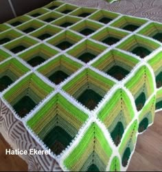 a green and white crocheted blanket sitting on top of a bed