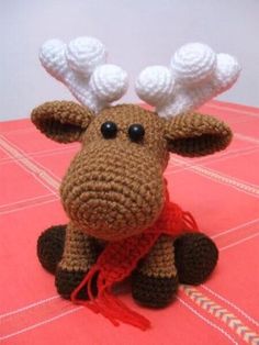 a crocheted moose sitting on top of a red table with white balls in its antlers