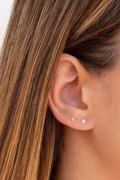 a woman's ear with two small white stones on it