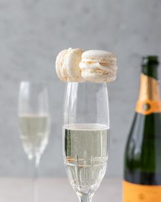 two champagne flutes with white wine in the foreground and bottle of champagne in the background