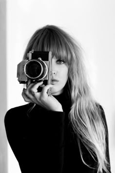 a black and white photo of a woman taking a selfie with an old camera