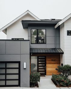 a modern house with two garages on the front and one above it's door