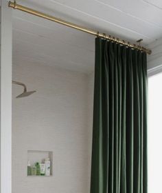 a bath tub sitting next to a window covered in green curtained drapes