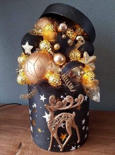 a black and gold christmas tree in a tin can on a wooden table with stars