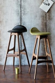 two stools sitting next to each other in front of a wall with a clock on it