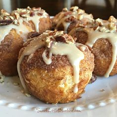 a white plate topped with donuts covered in icing and nuts on top of it