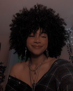 a woman with an afro is smiling at the camera while wearing necklaces and earrings