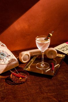 an old - fashioned phone, martini glass, and other items are sitting on a table