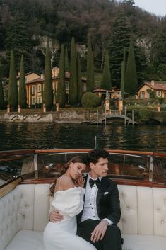 a bride and groom sitting on the back of a boat