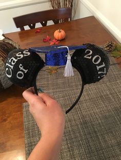 a hand holding a mickey mouse ears hat with the words class of 2017 on it