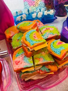 there are many pieces of colorful cake on the table with utensils in front of them