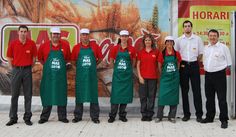 a group of people standing in front of a food truck with aprons and hats on