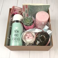 a box filled with lots of different items on top of a white wooden floor next to a cup